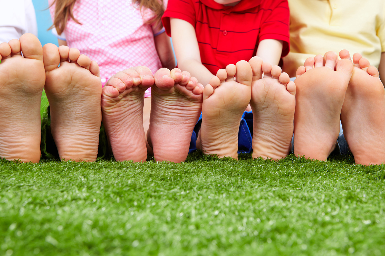 A group of children with their feet on the grass.